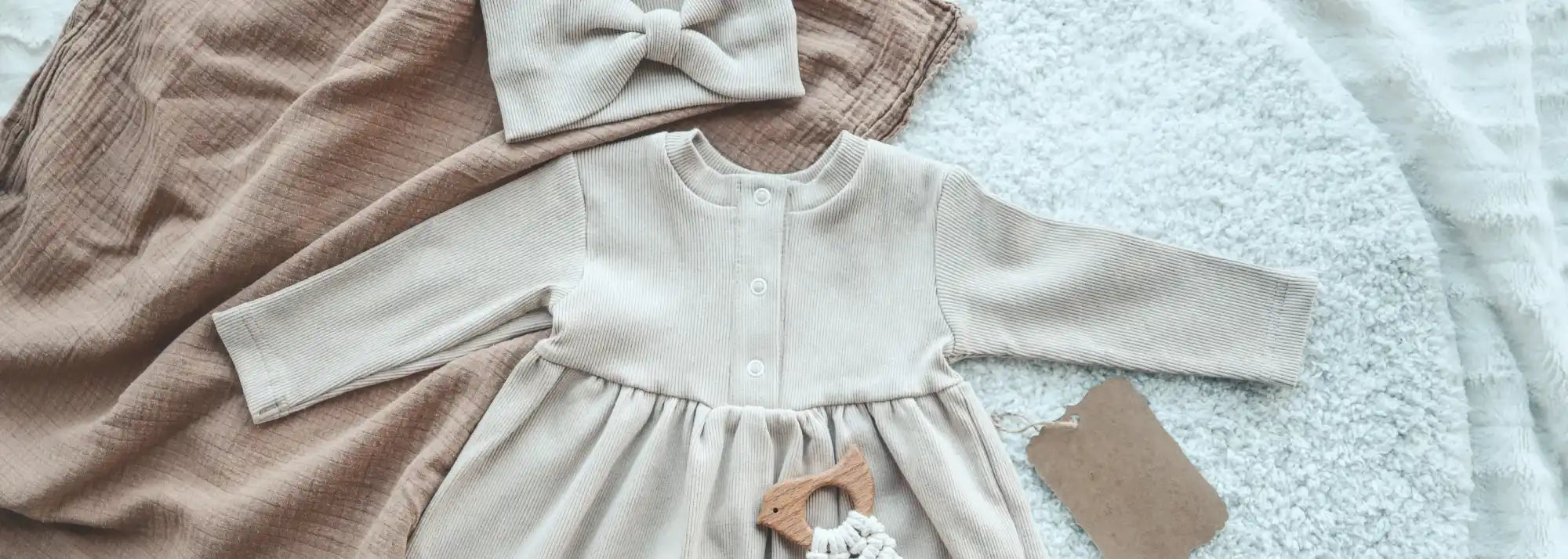 Vestido de bebê bege com faixa para cabeça combinando.